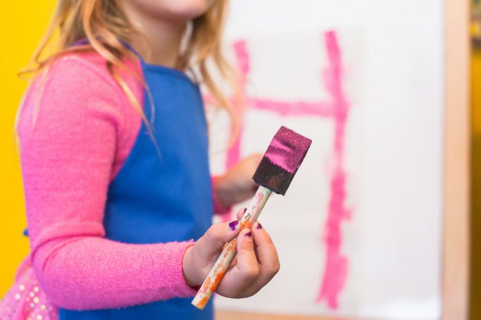 child paints with pink paint brush