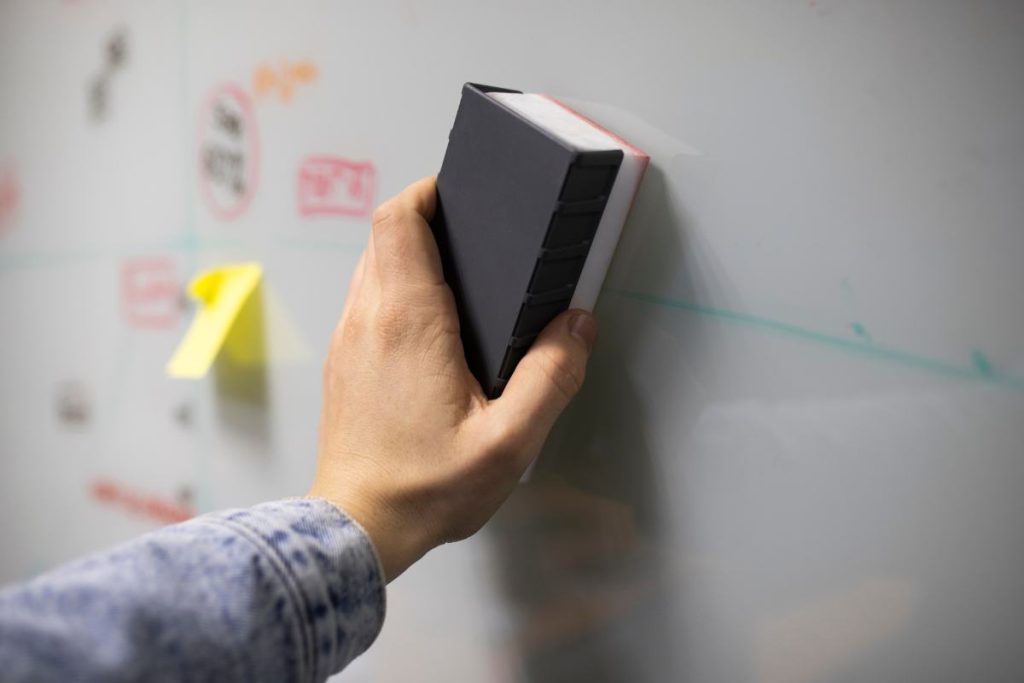 person cleaning whiteboard with eraser