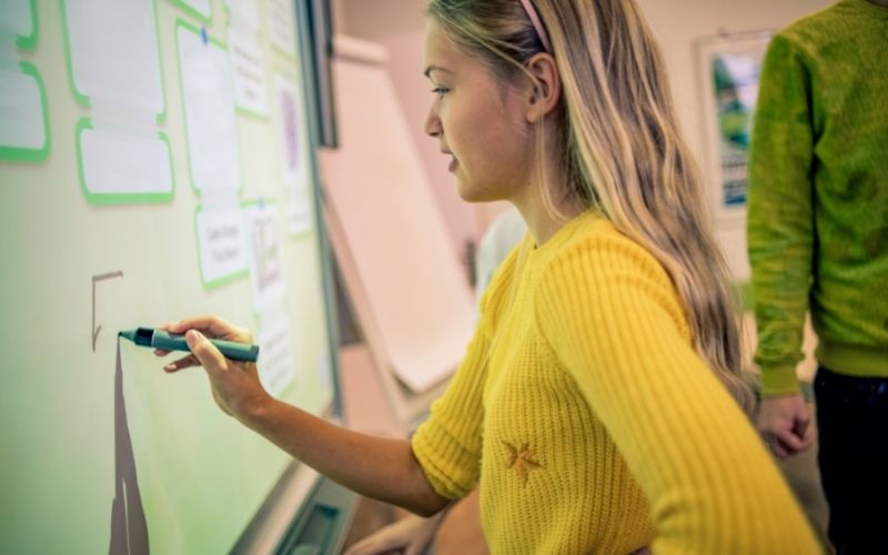 student writes on interactive whiteboard