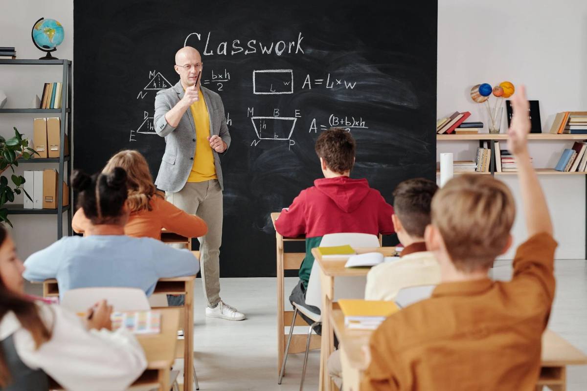 Kids raising their hands to answer the teacher's questions during a class