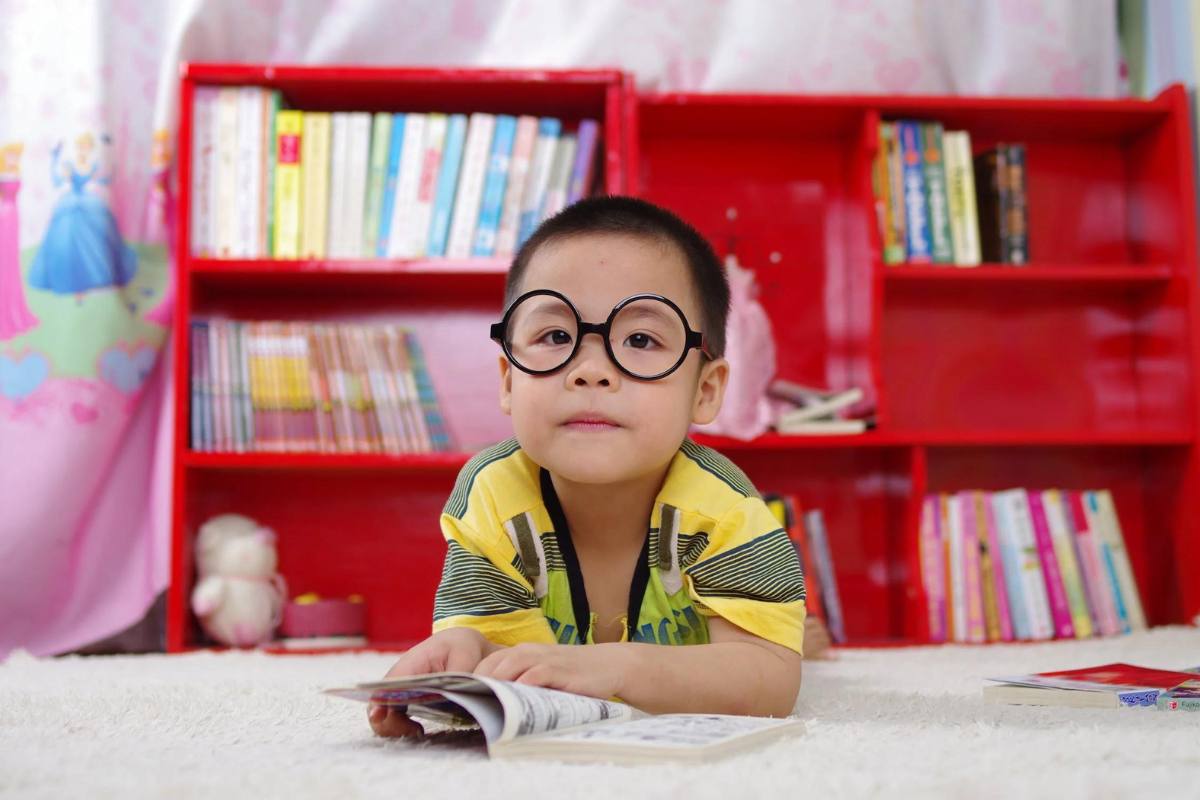 Young boy lying on the floor and reading a book
