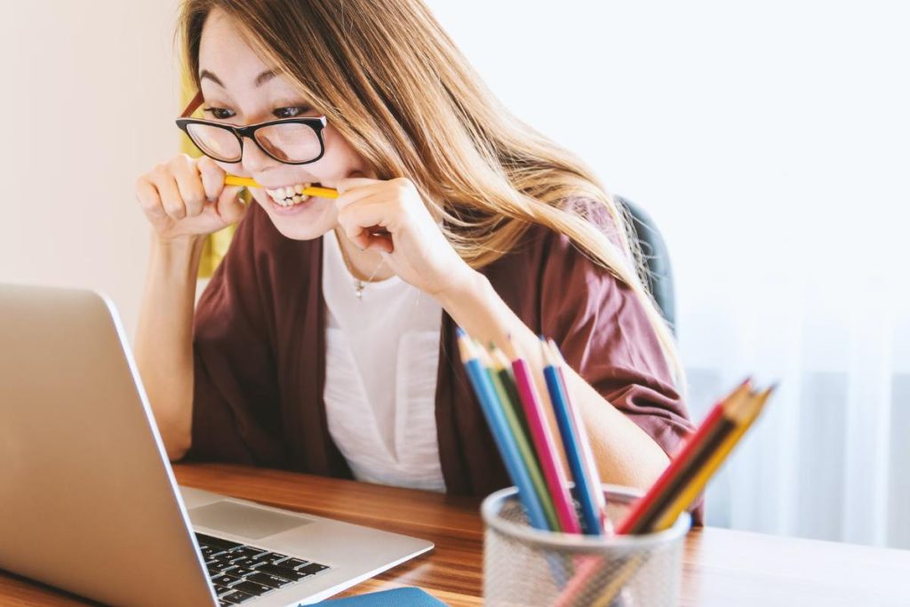 Student biting a pencil and researching tips to prepare for a college move-in day
